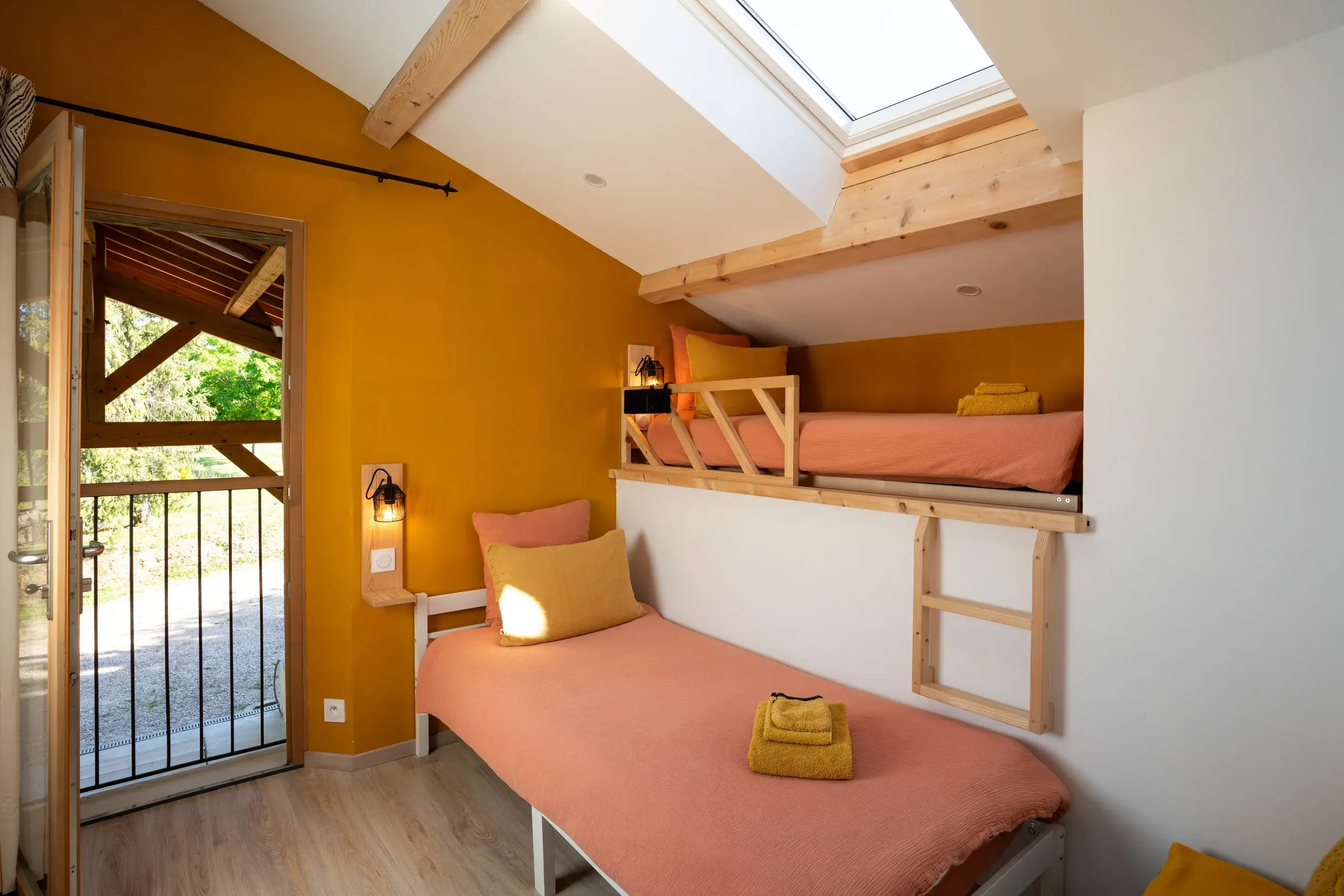 Deuxième chambre lumineuse avec lits superposés, velux et linge de lit rose