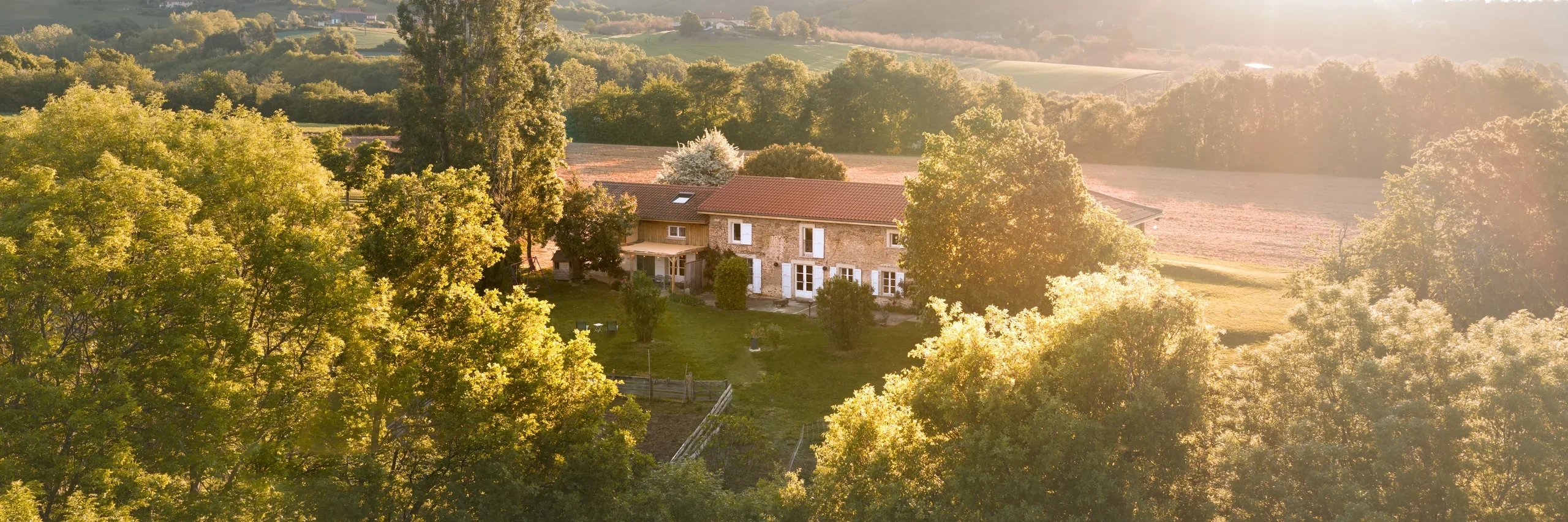 Vue aerienne du domaine L'Hospitalier dans son ecrin de verdure, lumiere doree de fin de journee
