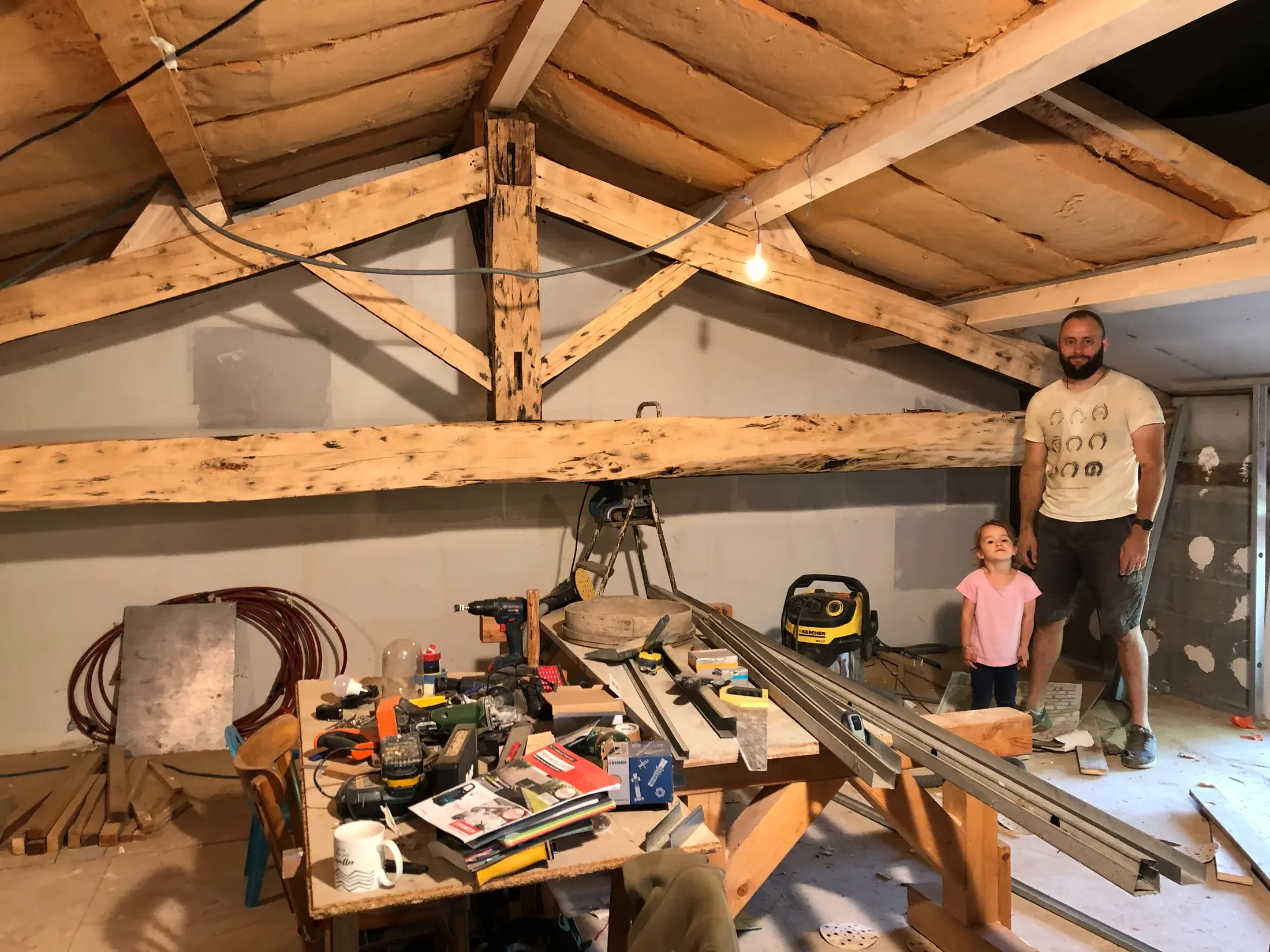 Arnaud et sa fille sous la charpente du gîte pendant les travaux
