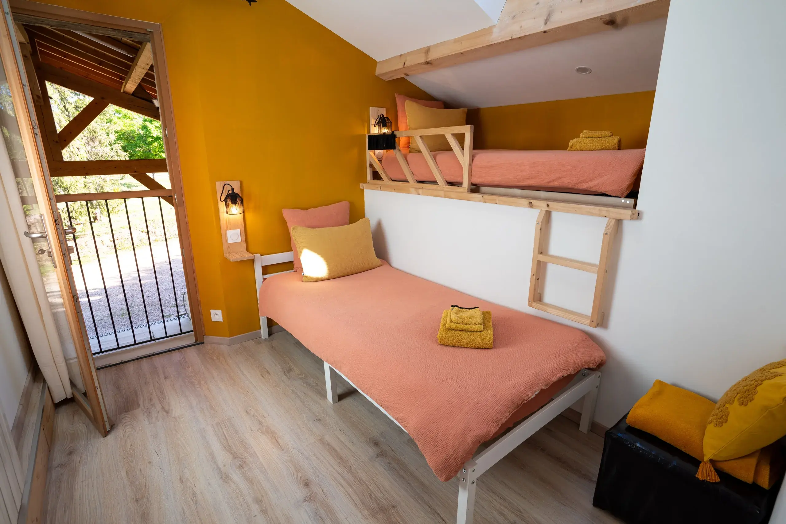 Chambre enfants avec lits superposes, lit simple, coussins jaunes et acces balcon