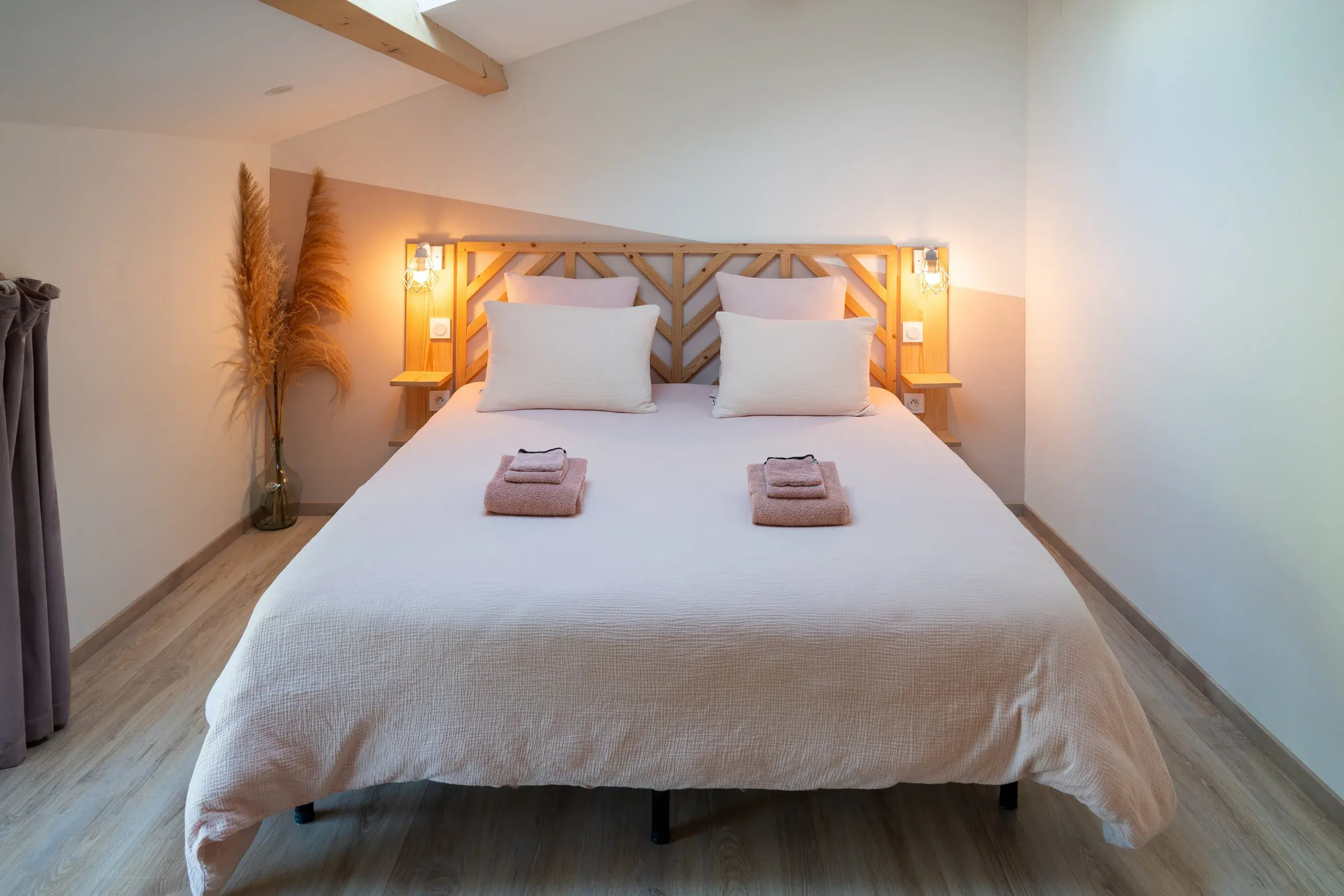 Chambre parentale avec lit double, poutres apparentes et linge de lit clair