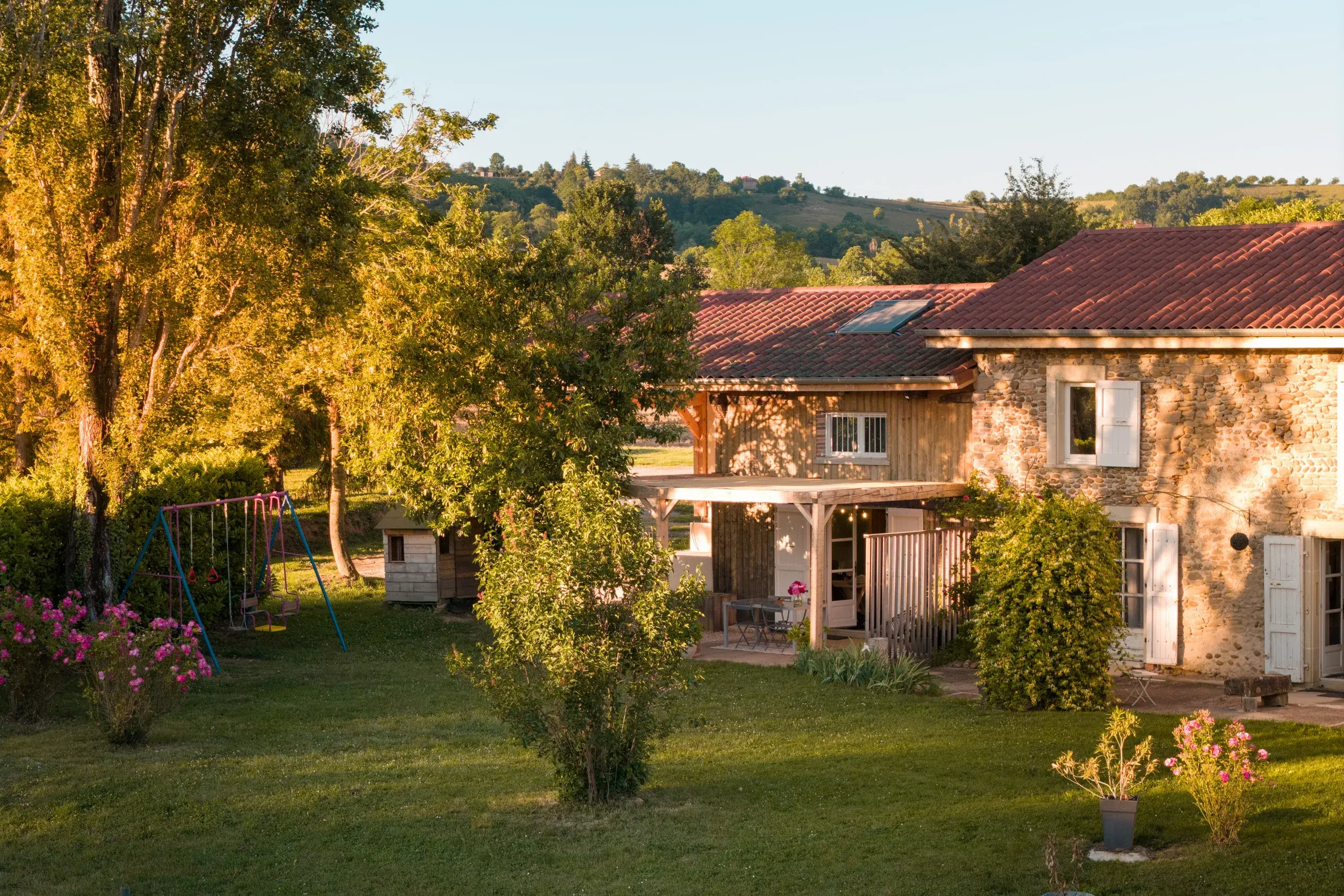 Jardin du gite L'Hospitalier au coucher du soleil, avec la maison et les collines en fond