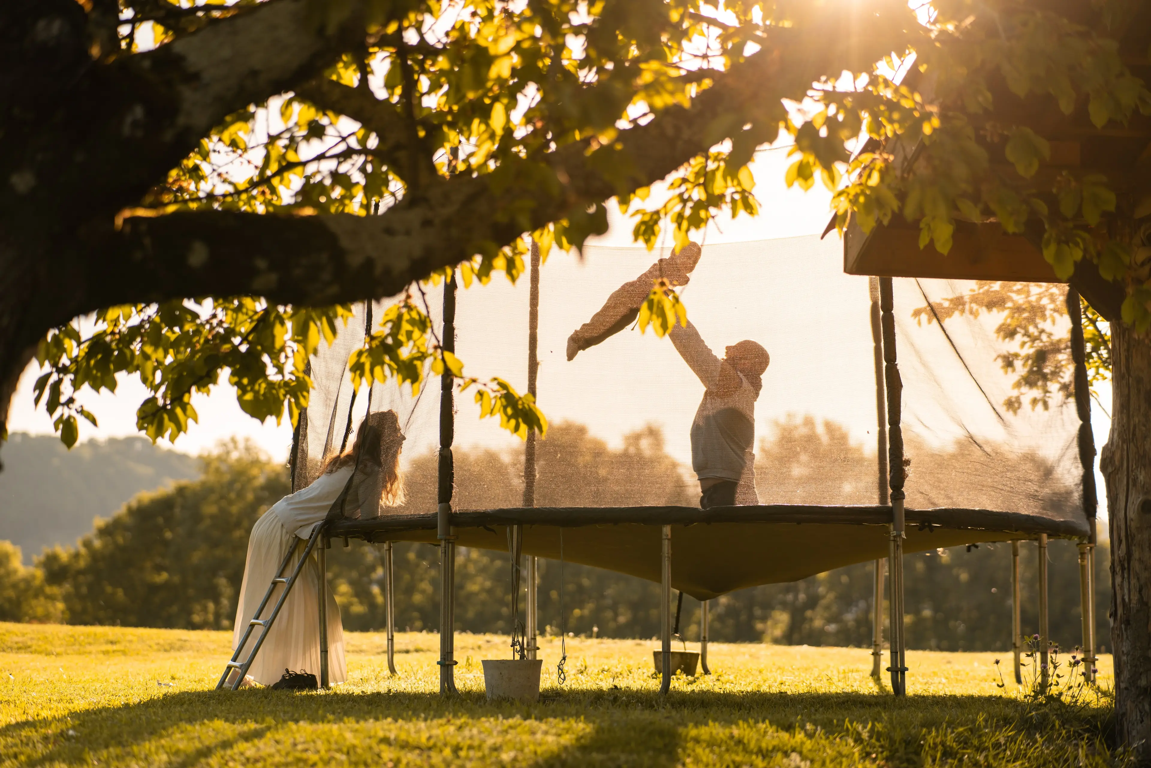 Trampoline dans le jardin du gîte L'Hospitalier, lumière dorée de fin de journée