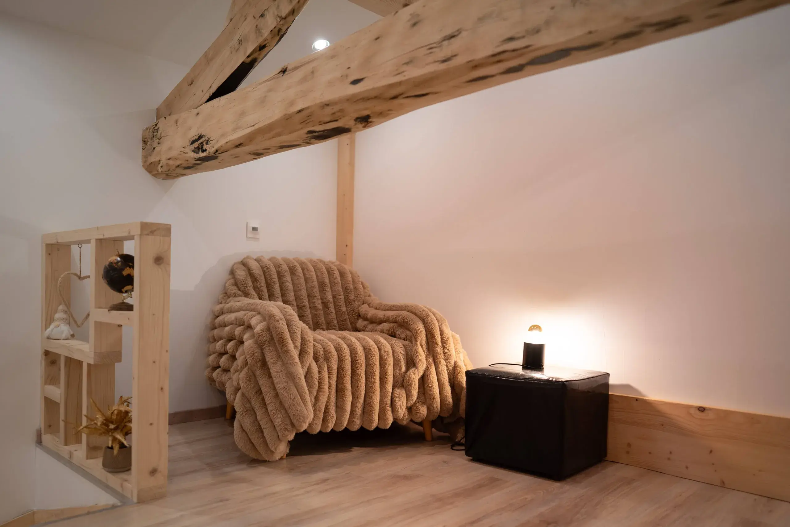 Coin lecture sous les poutres avec fauteuil et plaid dans le gite