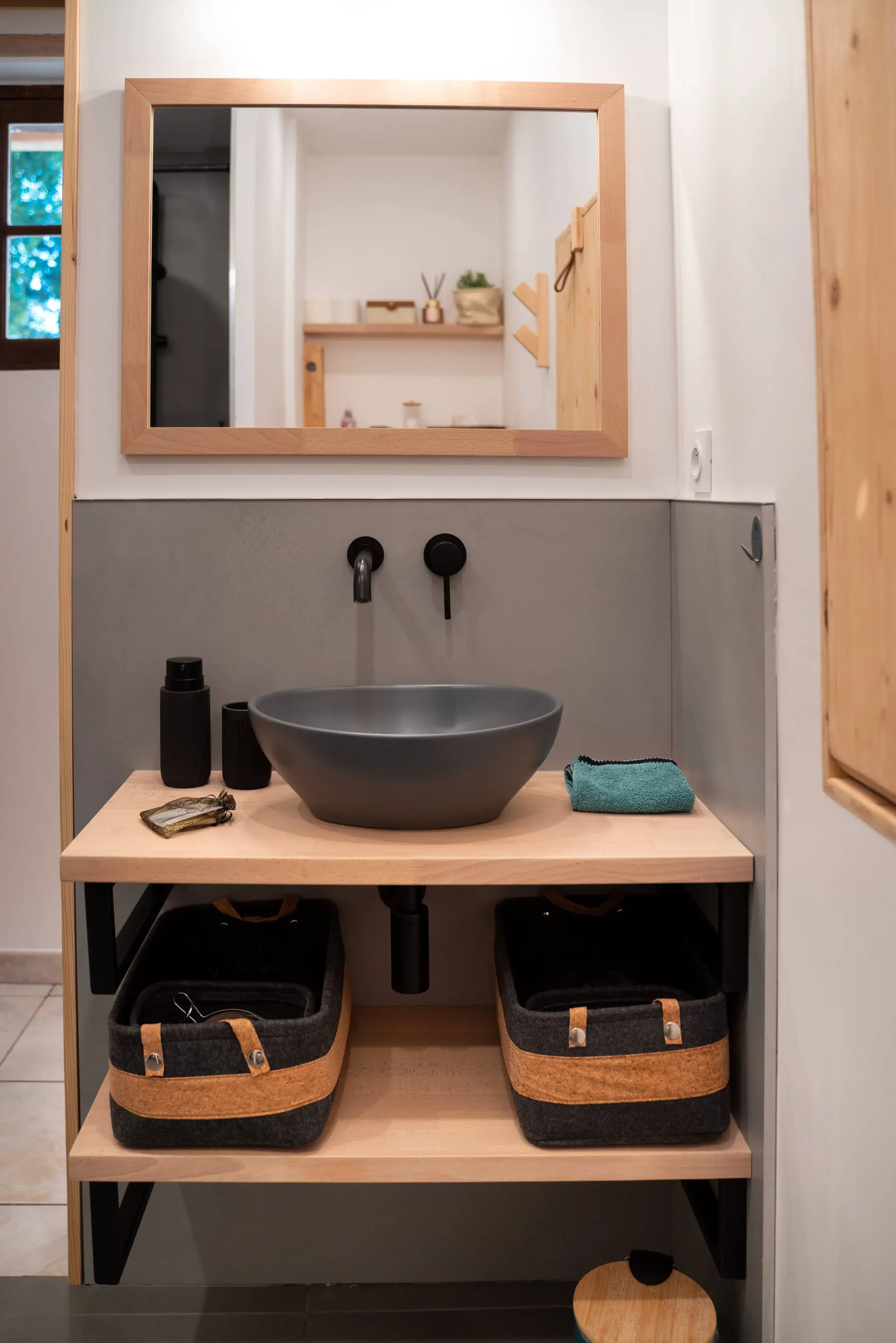 Vasque grise sur meuble en bois dans la salle de bain du gite